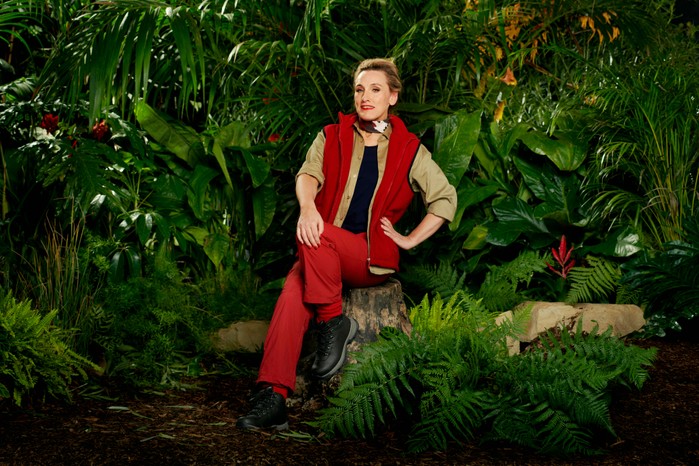 Grace-Dent-I'm-a-Celebrity I'm a Celebrity 2023 contestant Grace Dent wearing her camp gear while sitting on a log in front of some trees ahead of the 2023 season.